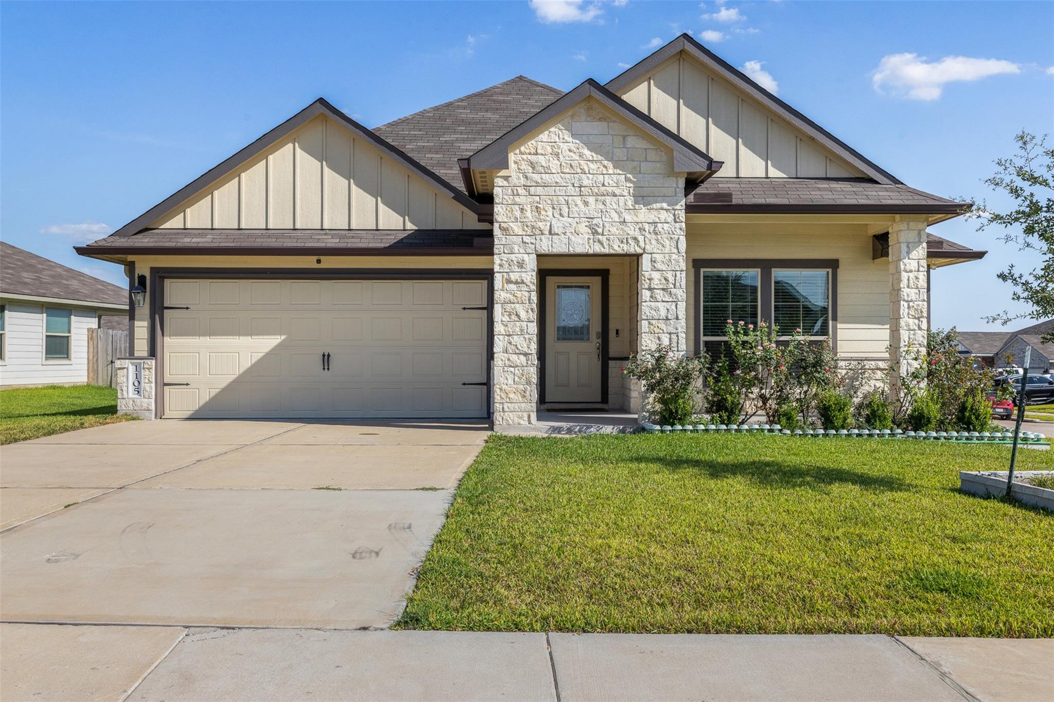 Single-story home with stone accents, a two-car garage, and a wide driveway.