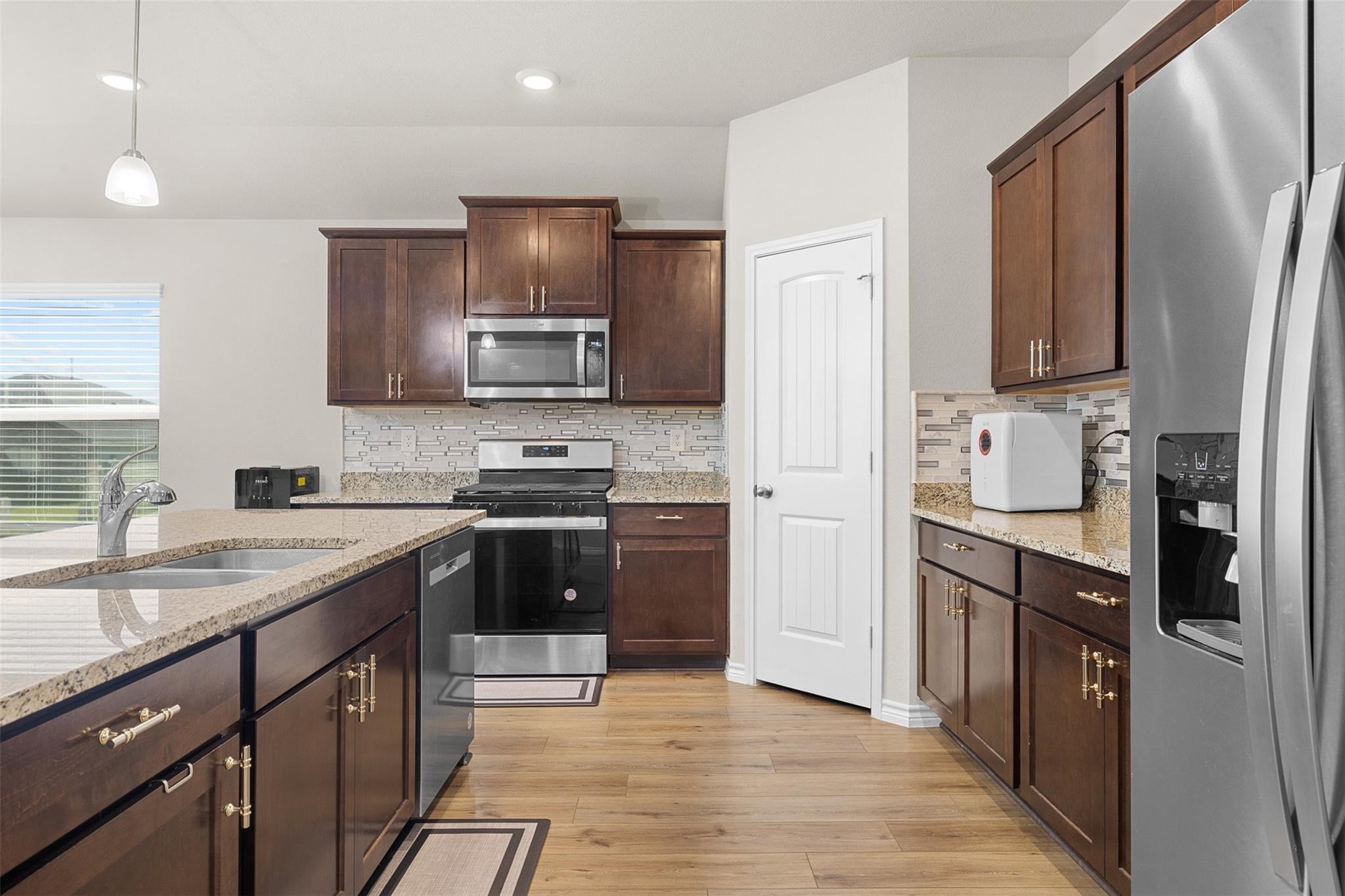 Kitchen with dark wood cabinets, granite counters, stainless appliances, and a peninsula sink.
