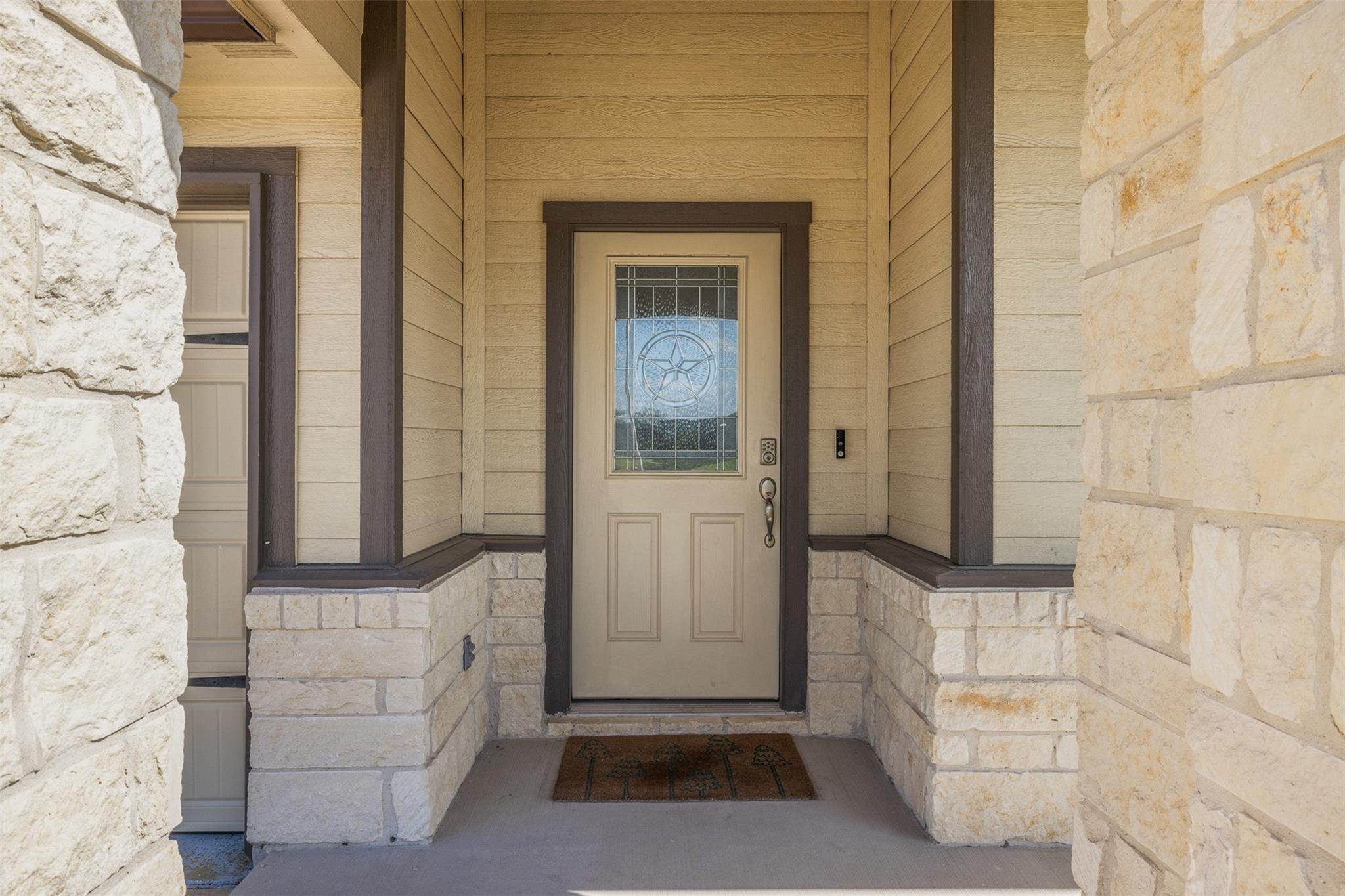 Covered front entry with a decorative glass star in the door and light stone walls.