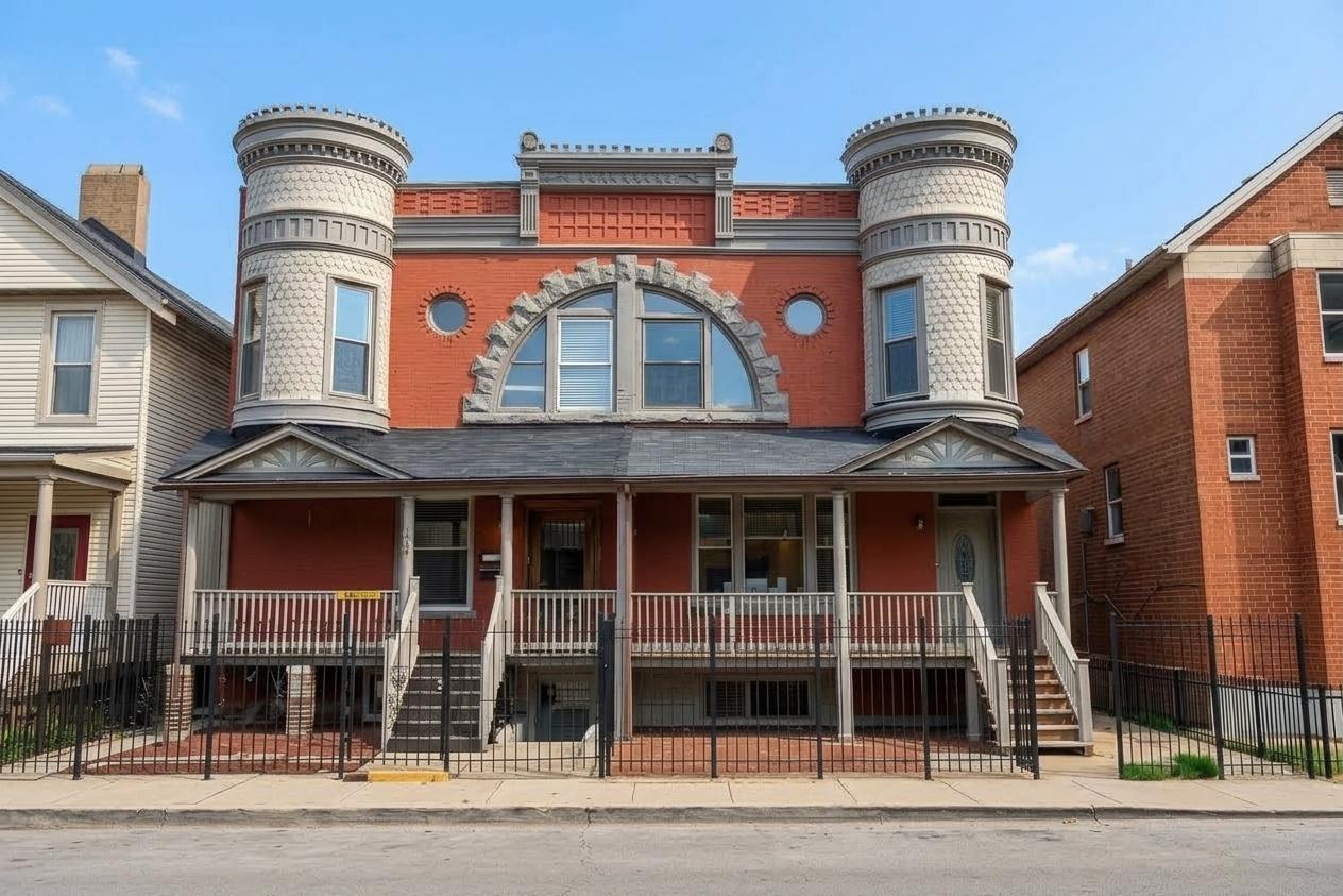 Red-brick residence with ornate round turrets, an arched window, and a raised front porch.