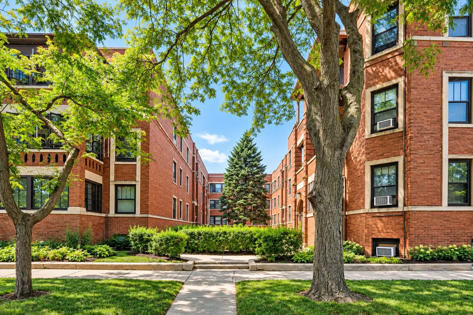 Red-brick apartment buildings frame a leafy courtyard with mature trees and a central sidewalk.