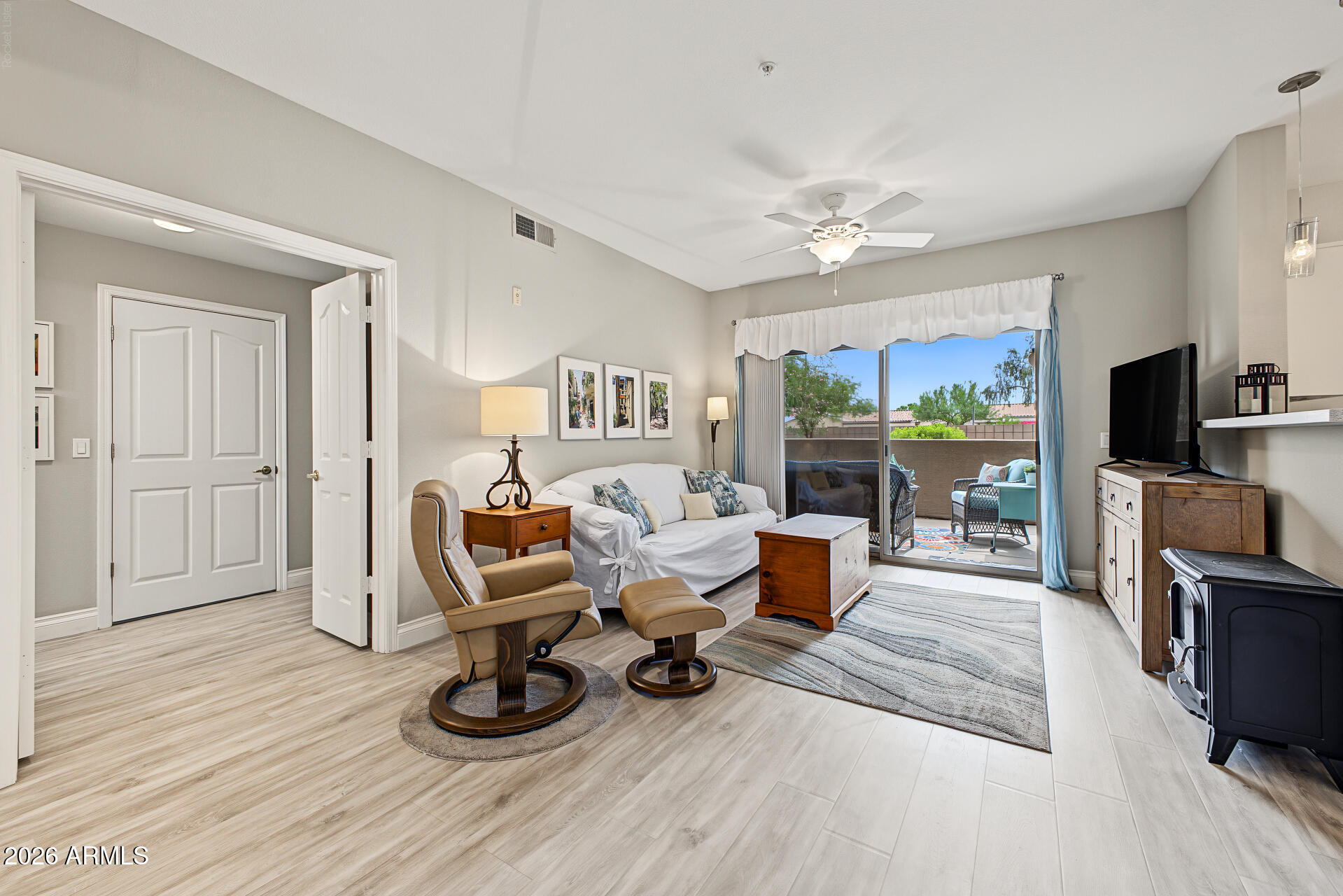 Living room with a white sofa, leather recliner, and sliding doors to a furnished patio.