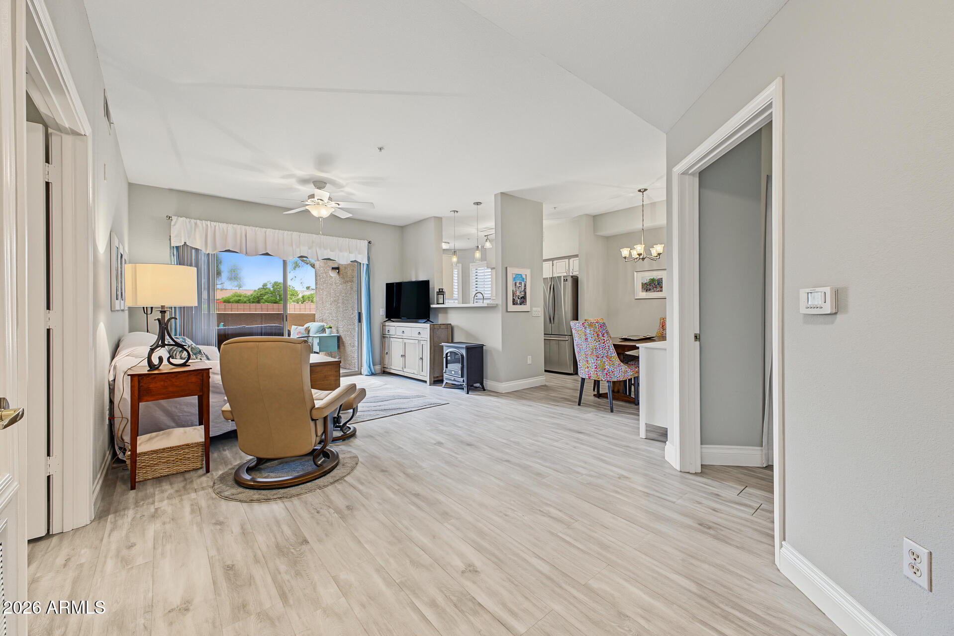 Open-plan living room with ceiling fan, sliding doors, and dining area beside the kitchen
