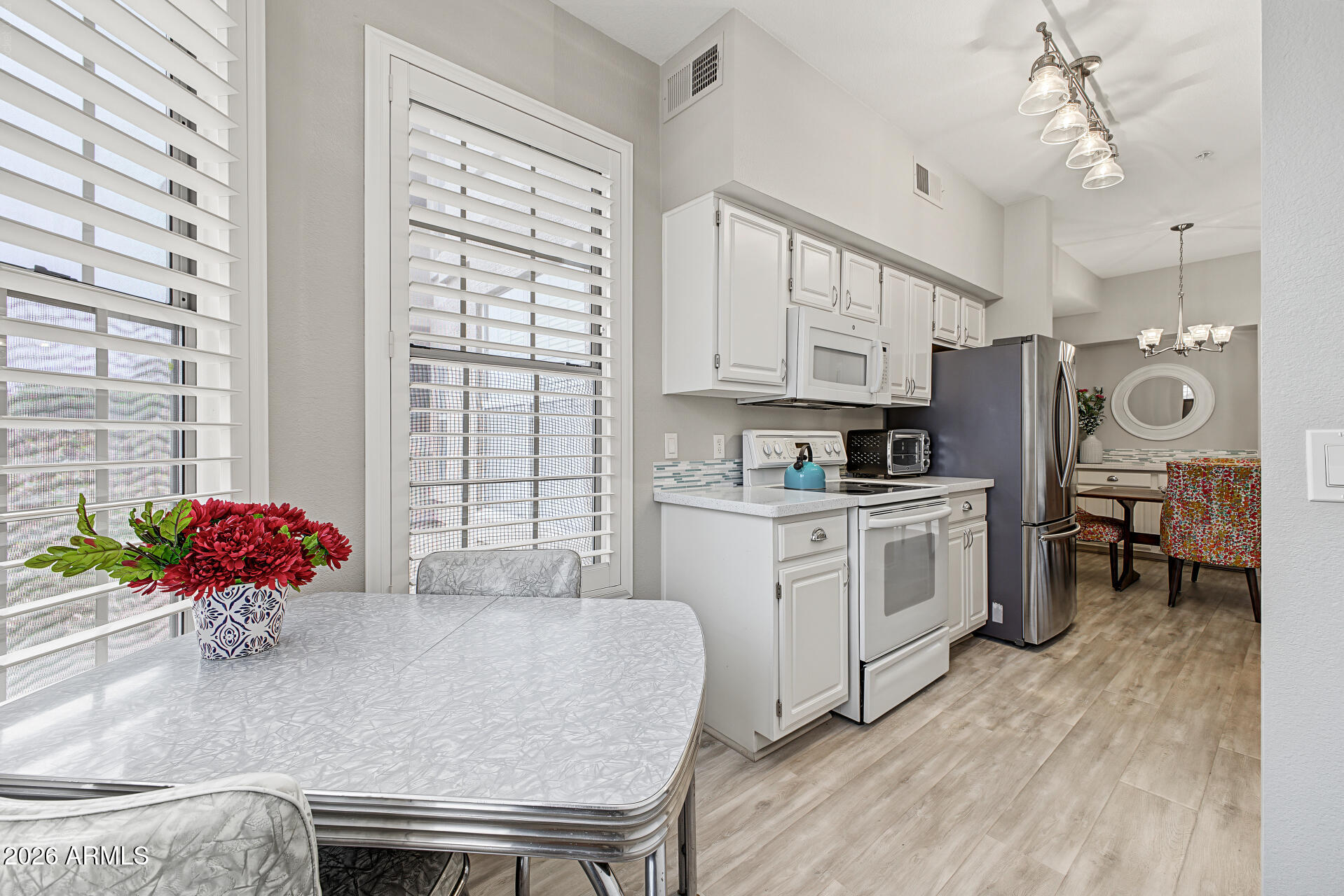 Kitchen and dining area with white cabinetry, stainless-steel appliances, and a colorful dining nook.