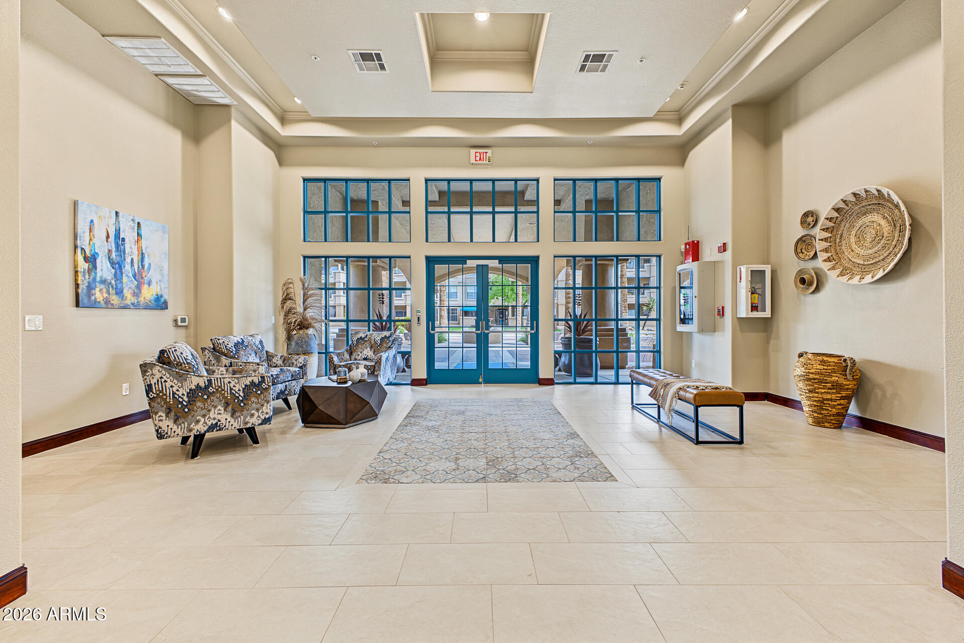 Apartment lobby with patterned seating and blue-framed glass entrance doors.