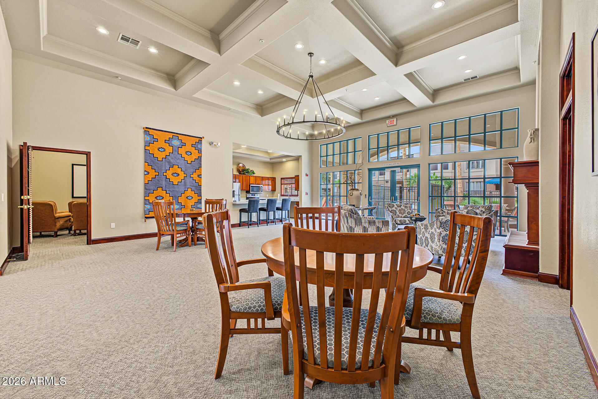Furnished dining and lounge area with a coffered ceiling, large windows, and kitchen bar seating.