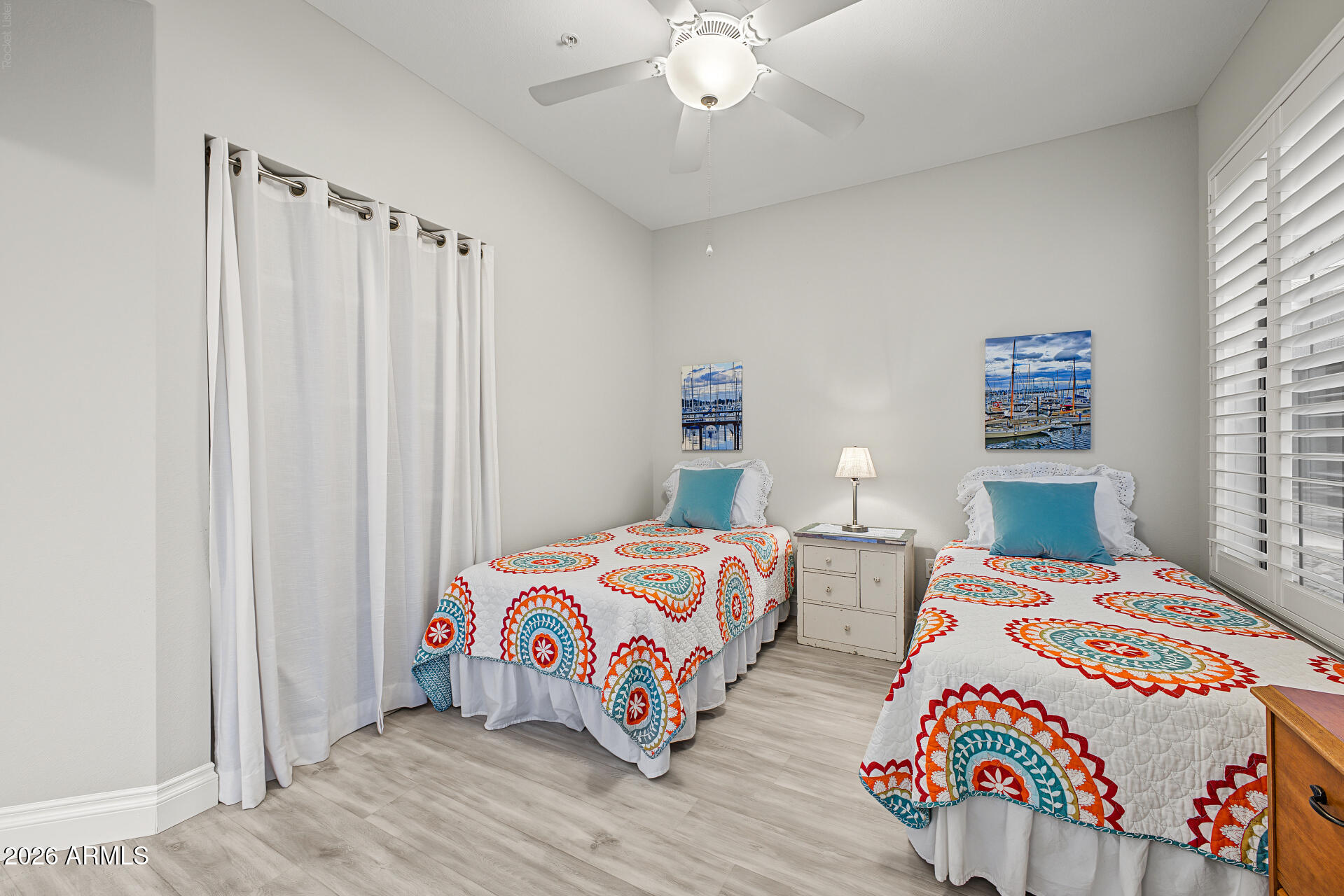 Bedroom with two twin beds in colorful patterned quilts and a nightstand between them.