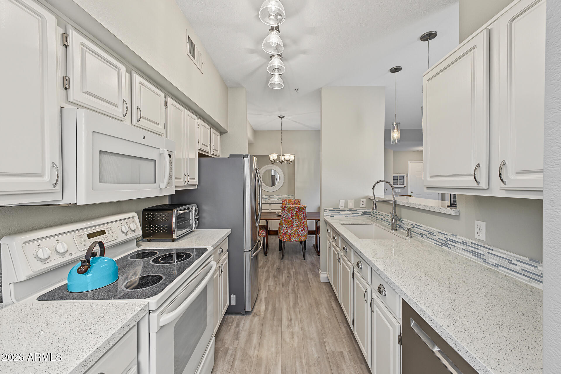 Kitchen with white cabinetry, stainless steel appliances, and a blue kettle on the stovetop.