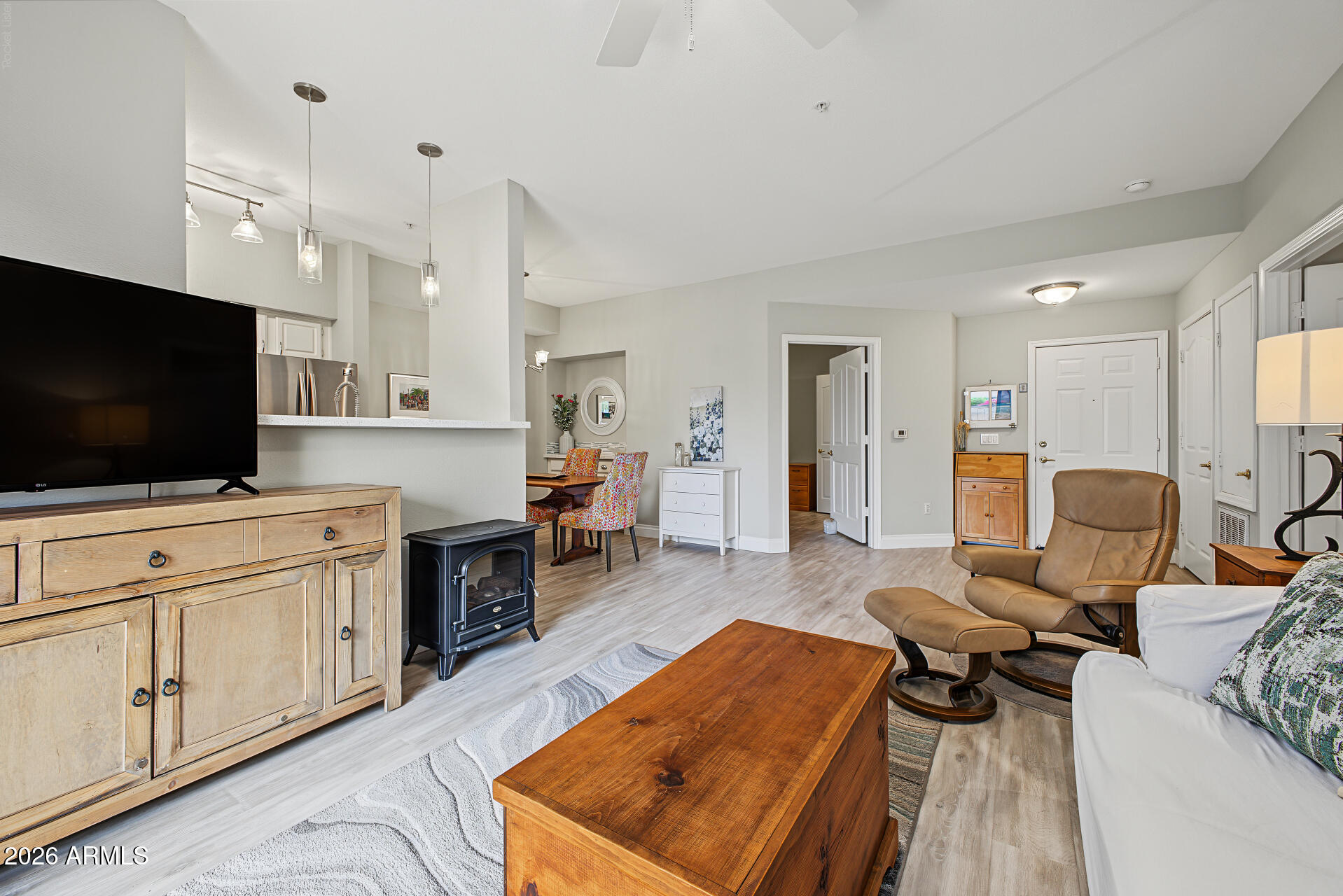 Open-plan living room with a tan recliner, rustic wood furniture, and adjoining dining area and kitchen.