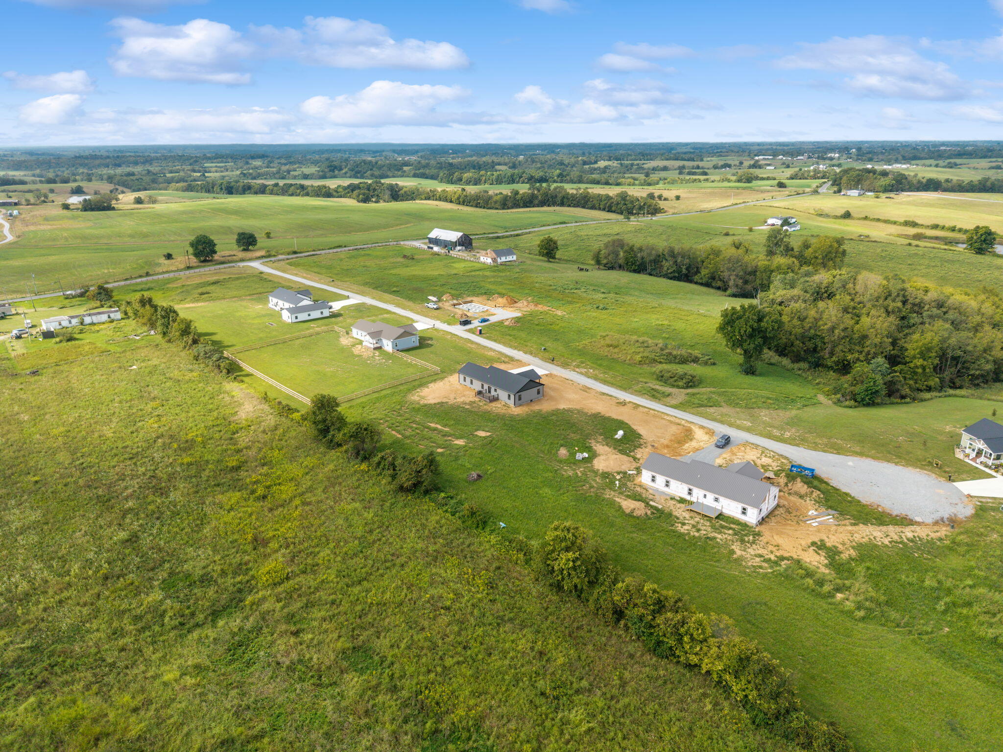 Aerial view of homes and open fields along a gravel road in the countryside.