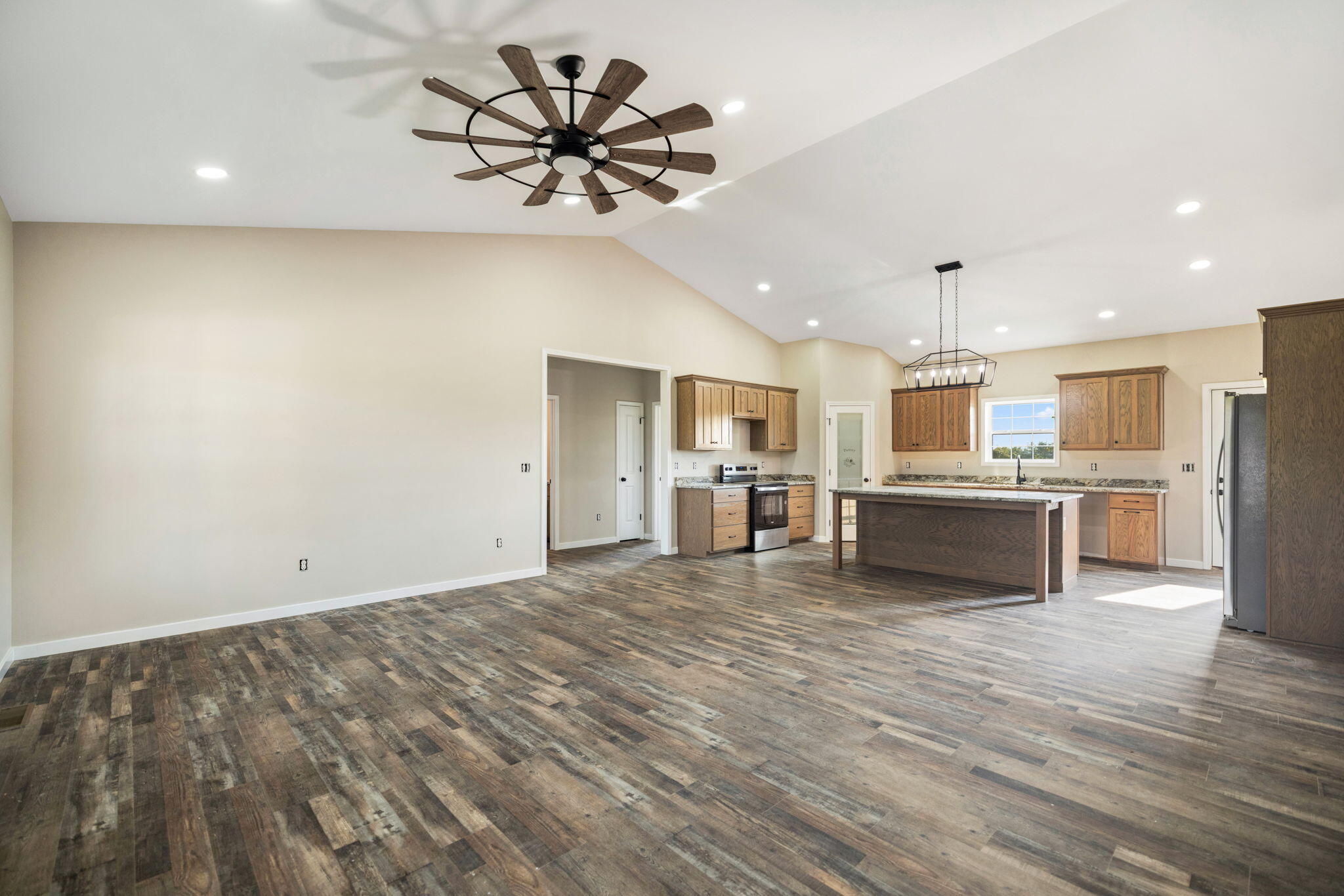 Open-plan kitchen with a large island, warm wood cabinets, and vaulted ceiling.