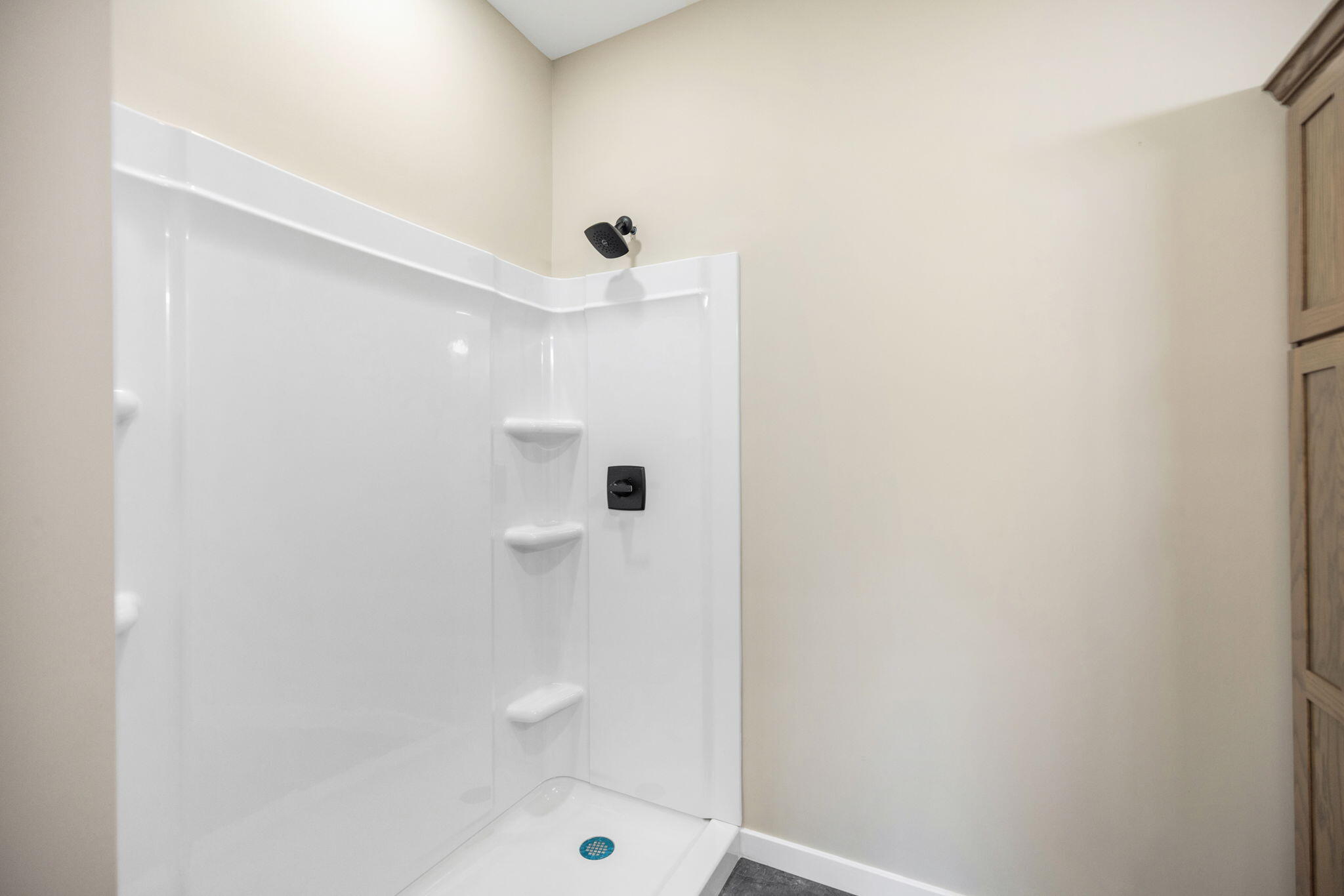 Bathroom shower with built-in corner shelves and black fixtures.