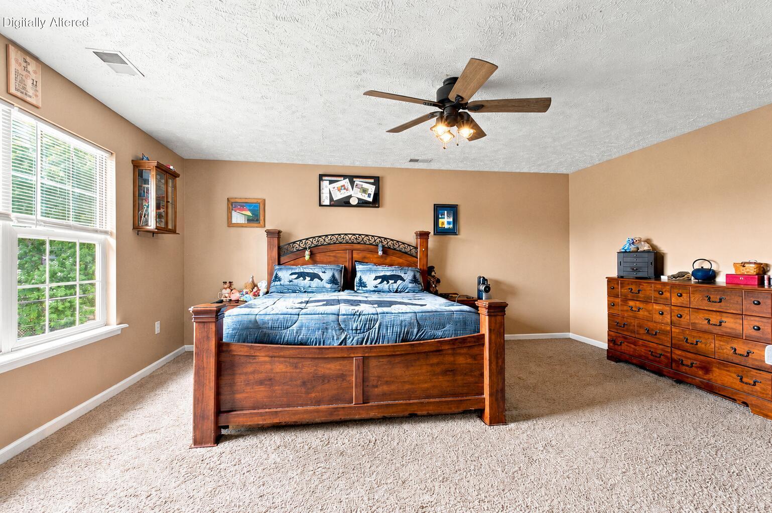 Furnished bedroom with a large wooden bed, blue bedding, and a bright window with white blinds.