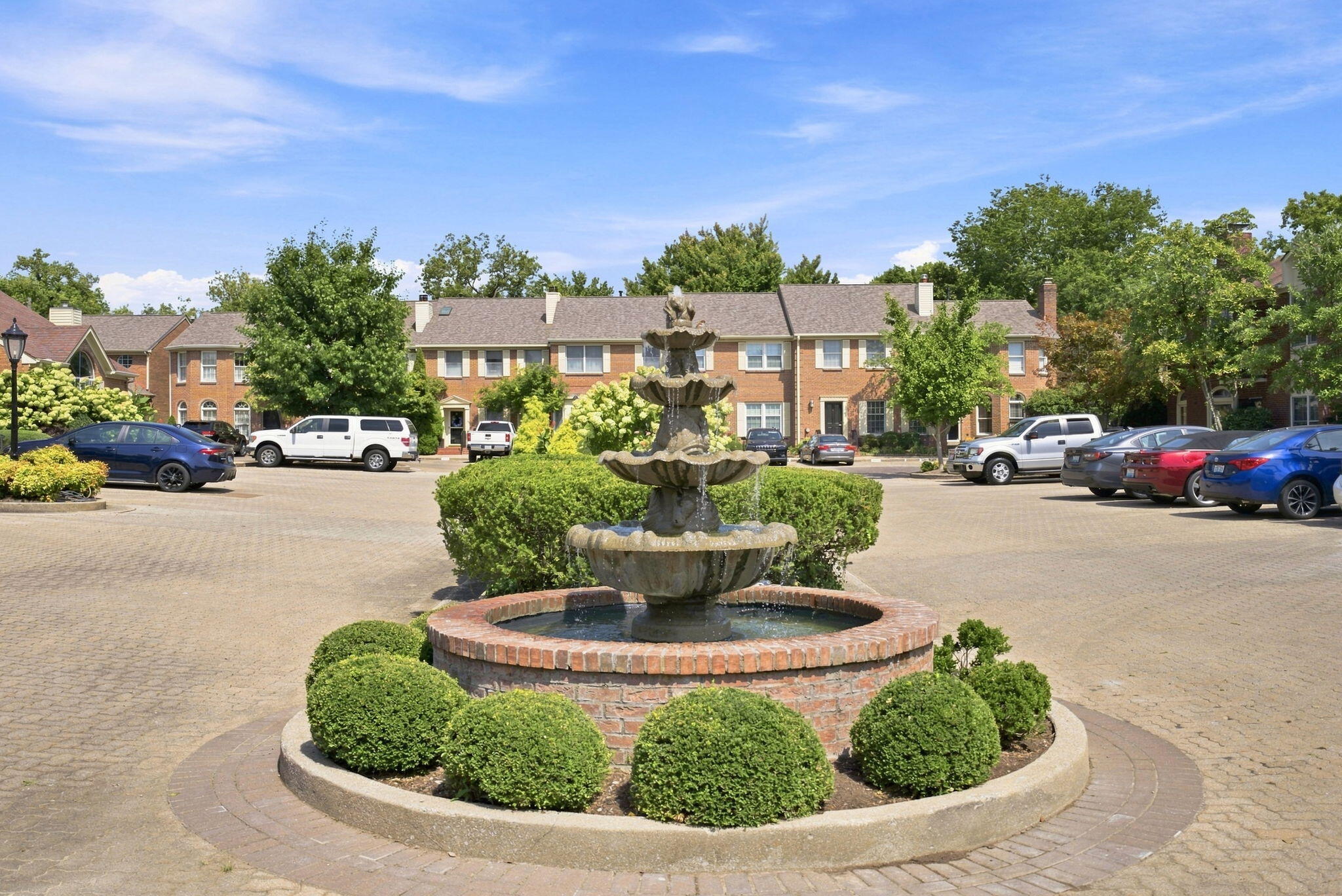 Brick townhomes surround a landscaped parking courtyard with a tiered fountain.