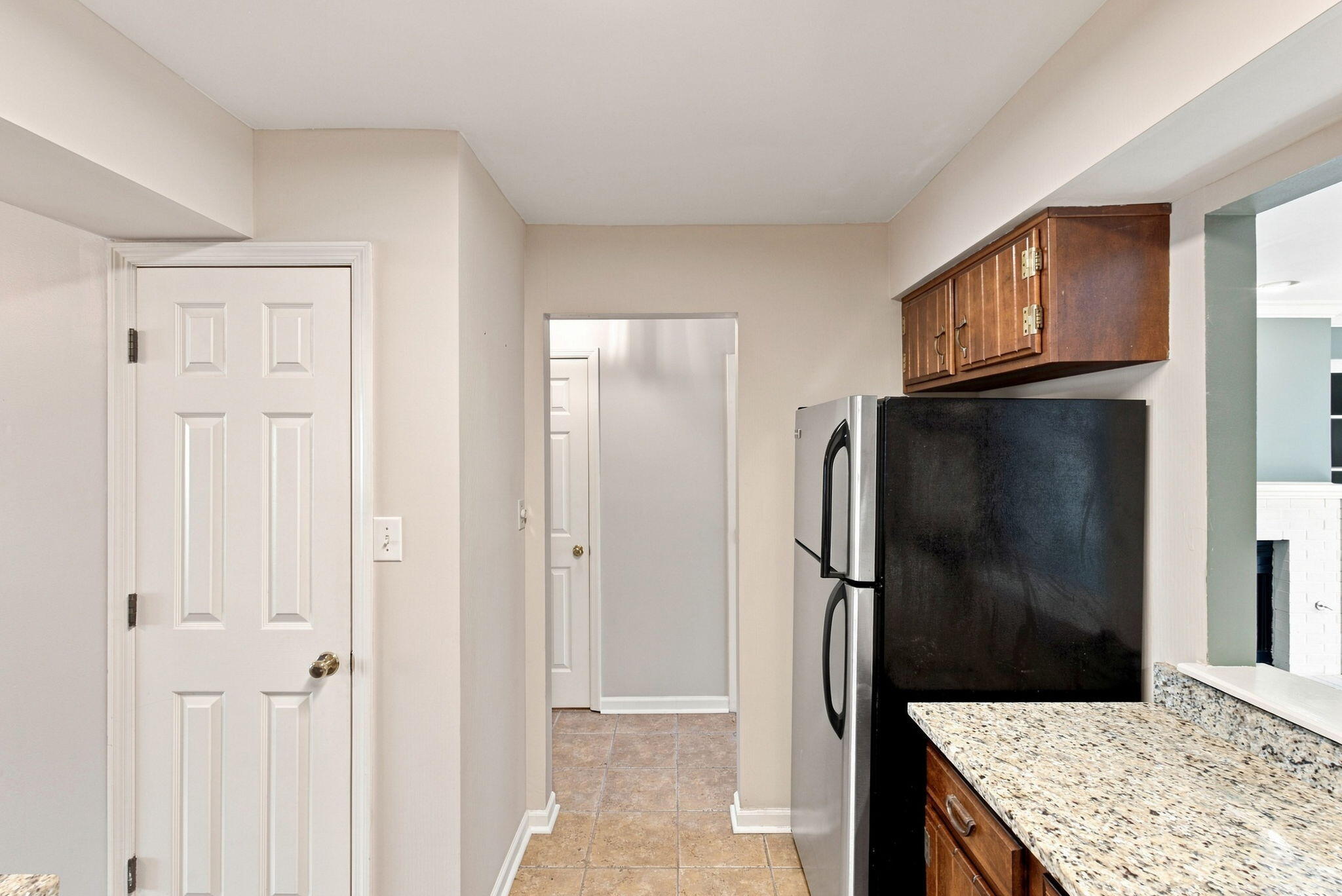 Kitchen with a stainless-steel refrigerator, dark wood cabinets, and granite countertops.