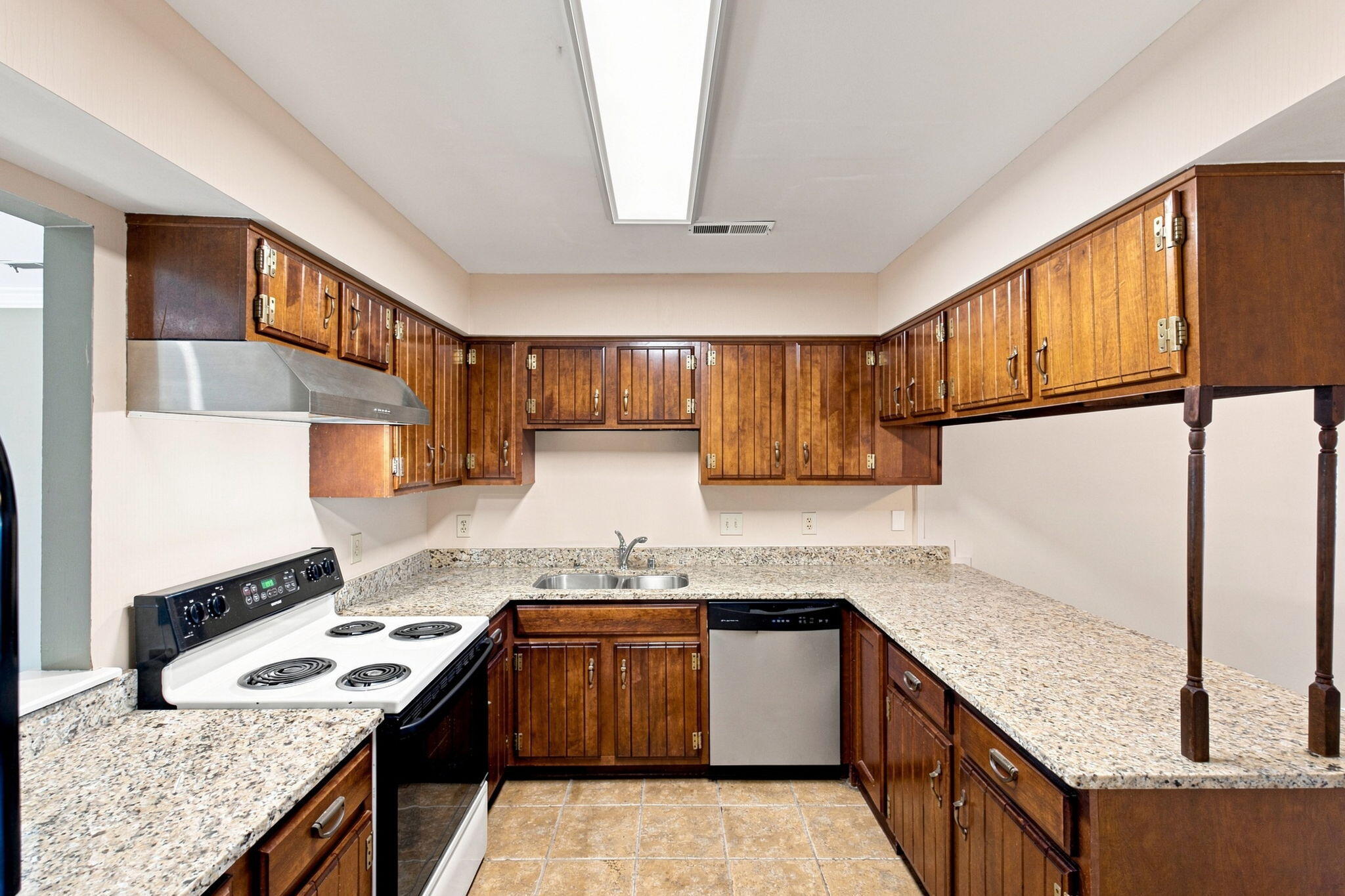 Kitchen with dark wood cabinetry, speckled countertops, and a white electric range.
