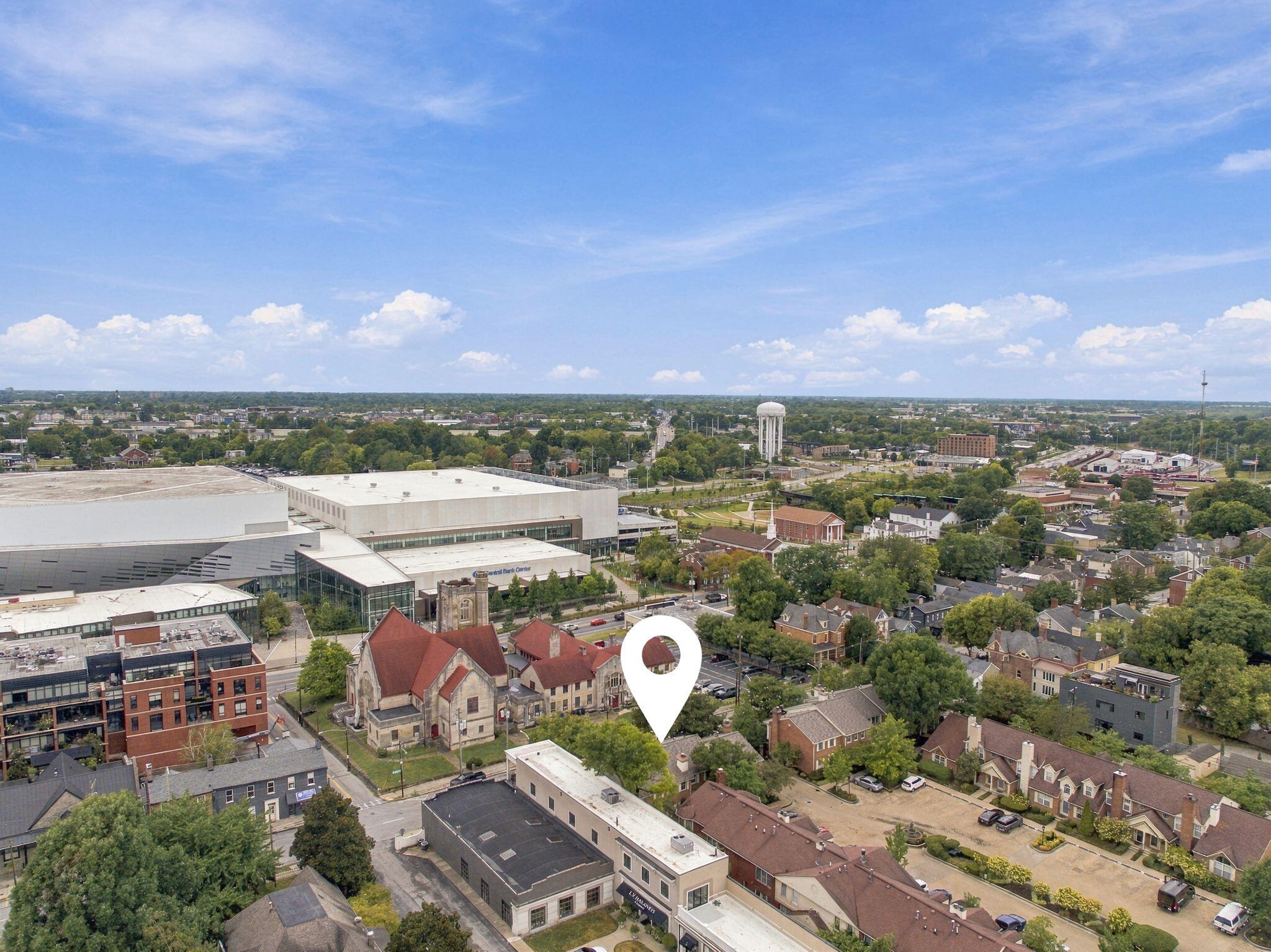 Aerial neighborhood view with a white location pin near a large convention center and water tower.