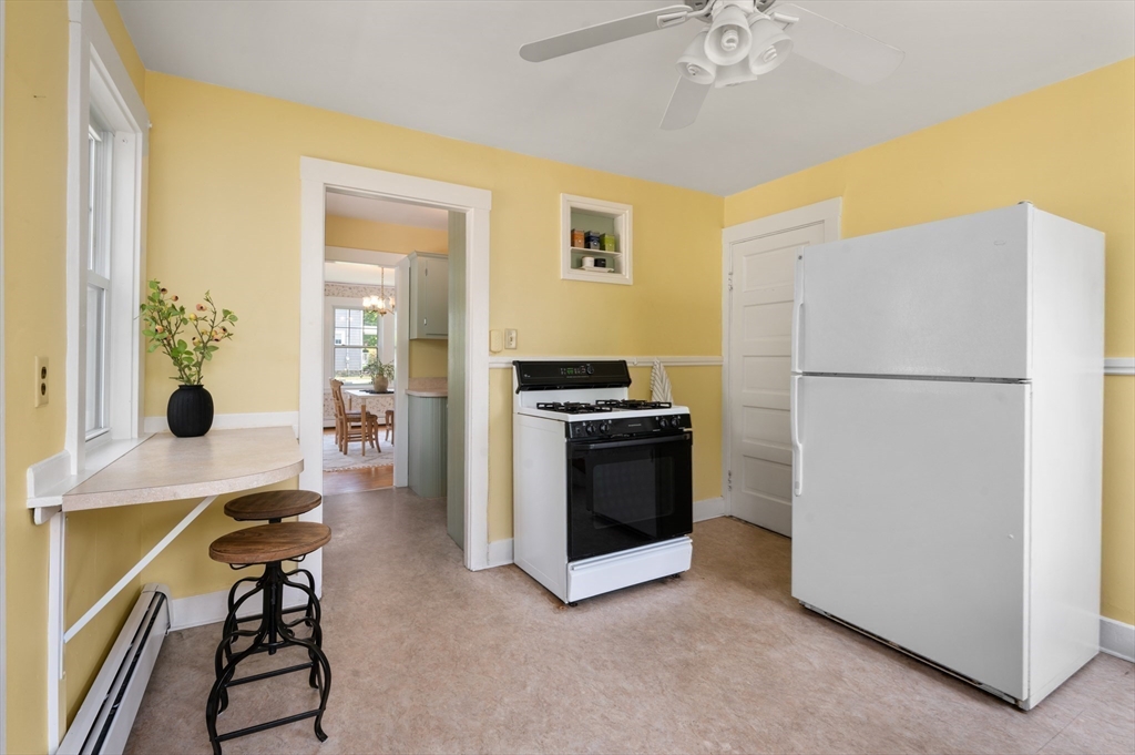 Kitchen with yellow walls, a large white refrigerator, and a counter with two stools.