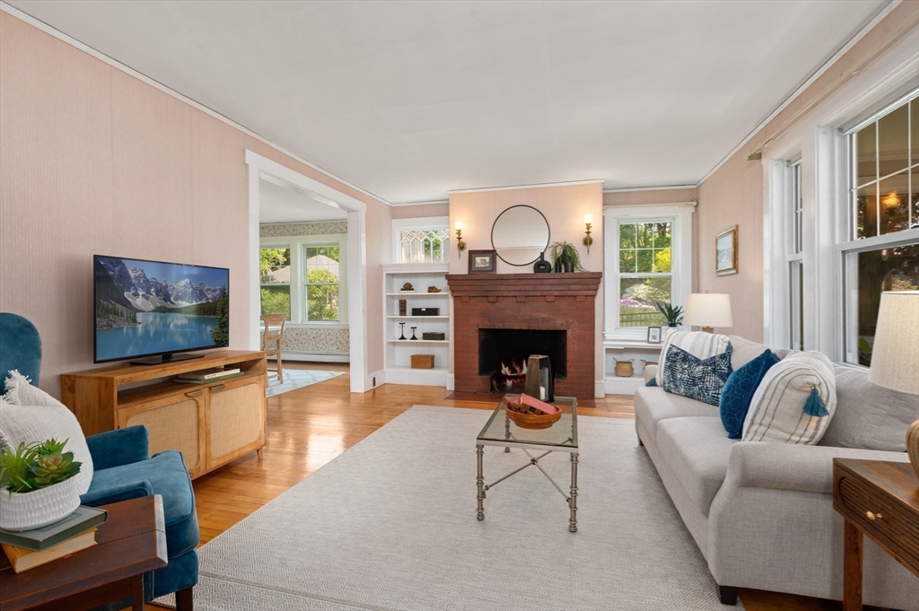 Living room with a brick fireplace, built-in shelves, and large windows.