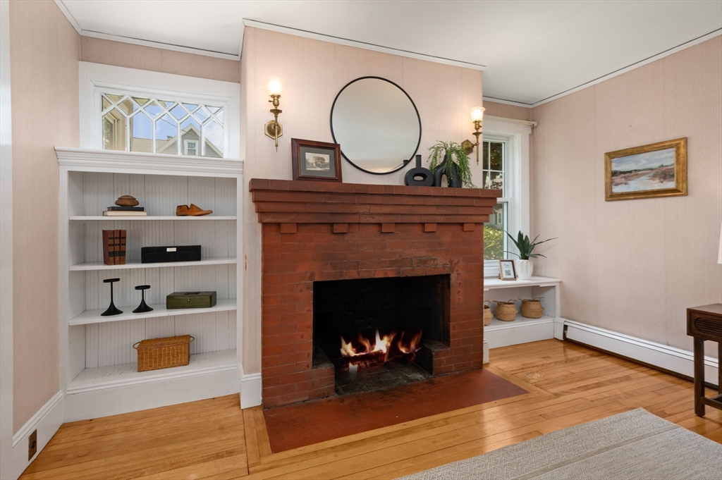 Living room with a red brick fireplace, built-in shelves, and hardwood floors.
