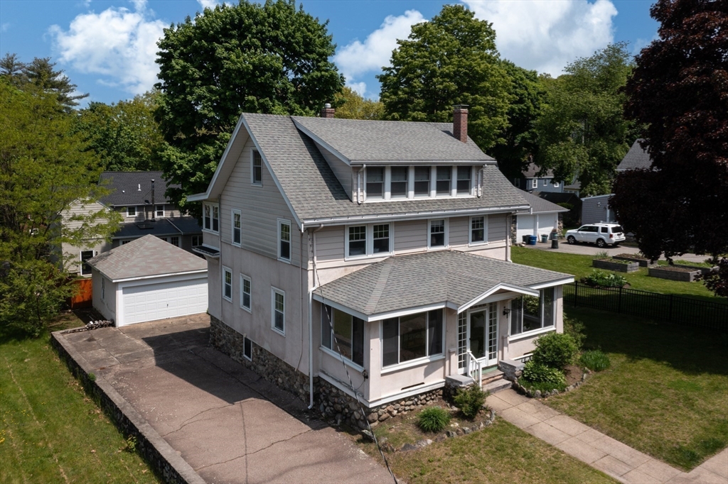 Two-story gray house with a screened porch, attached garage, and broad driveway, seen from above.