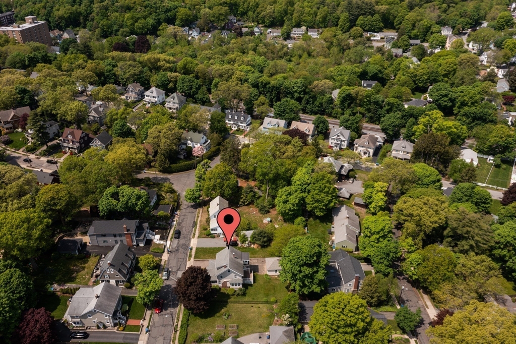 Aerial view of a detached home marked by a pin in a leafy residential neighborhood.