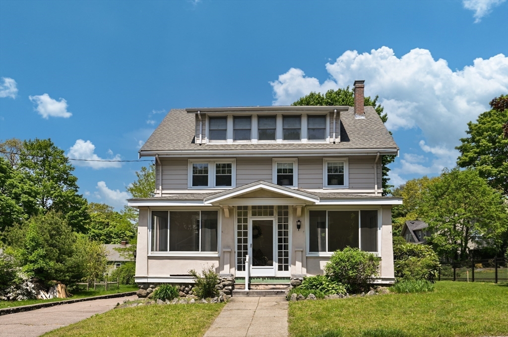 Two-story house with a broad dormer, enclosed porch, and walkway across the front lawn.