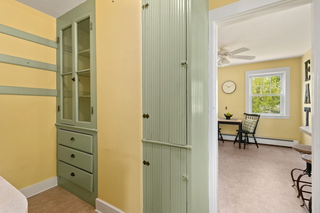 Kitchen with pale green built-ins and a view through to a sunny breakfast nook.