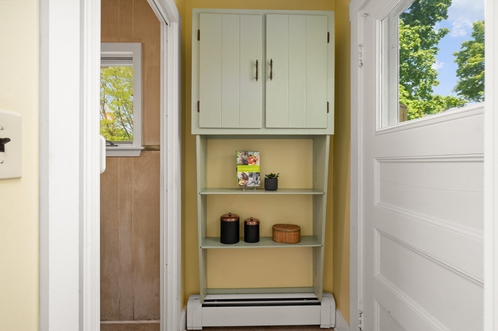 Hallway nook with pale green built-in shelves between a bathroom doorway and a white exterior door.