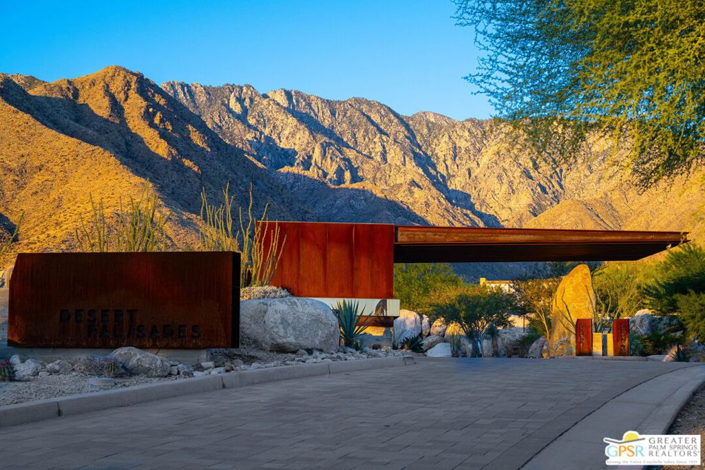 Desert Palisades entrance framed by desert landscaping and sunlit mountains.