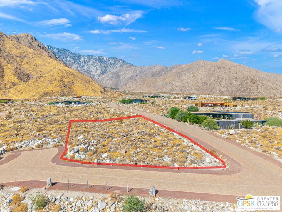 Vacant desert lot outlined in red, with paved streets and mountains behind it.