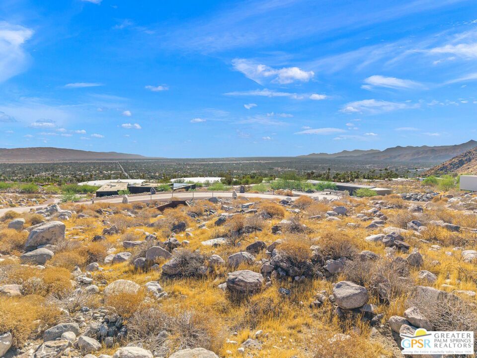 Desert hillside overlooking the Palm Springs valley, with distant mountains and scattered development.