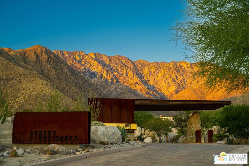 Desert Palisades entrance framed by desert landscaping and sunlit mountains.