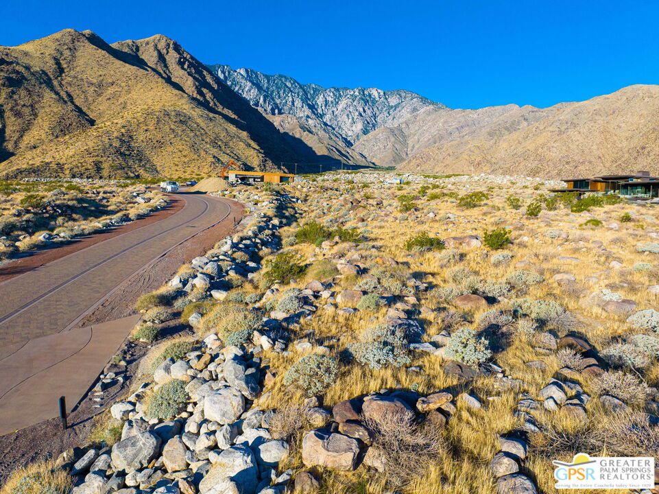 Rocky desert homes and a curving road beneath the mountains.