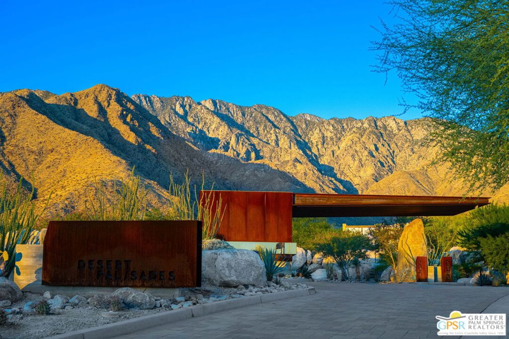 Desert Palisades entrance sign and modern gate beneath sunlit mountains.