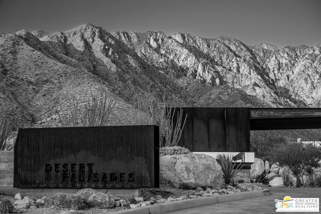 Desert Palisades entrance sign and desert landscaping beneath the Palm Springs mountains.