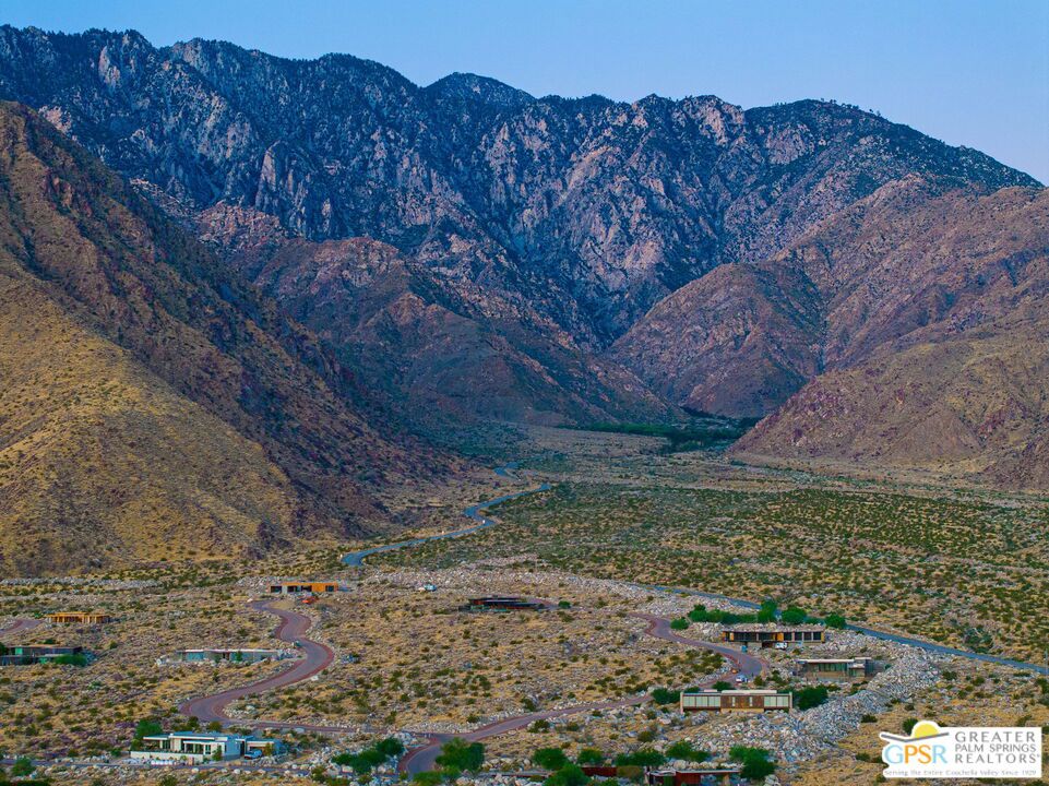 Desert homes and winding roads spread beneath rugged mountains.