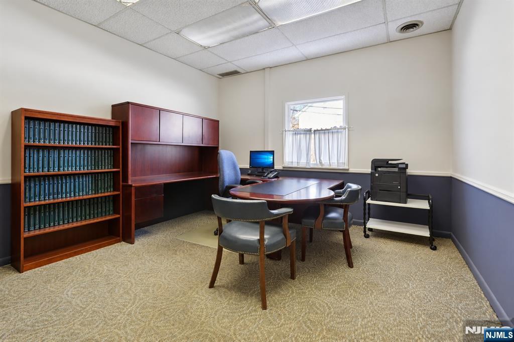 Office with a round meeting table, wood cabinetry, and a bookcase of binders.