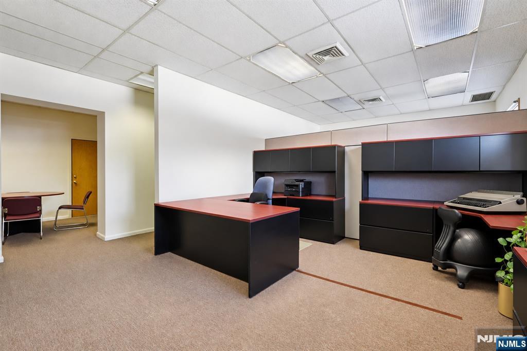 Furnished office with black-and-red desks, built-in cabinets, and carpeted floor.