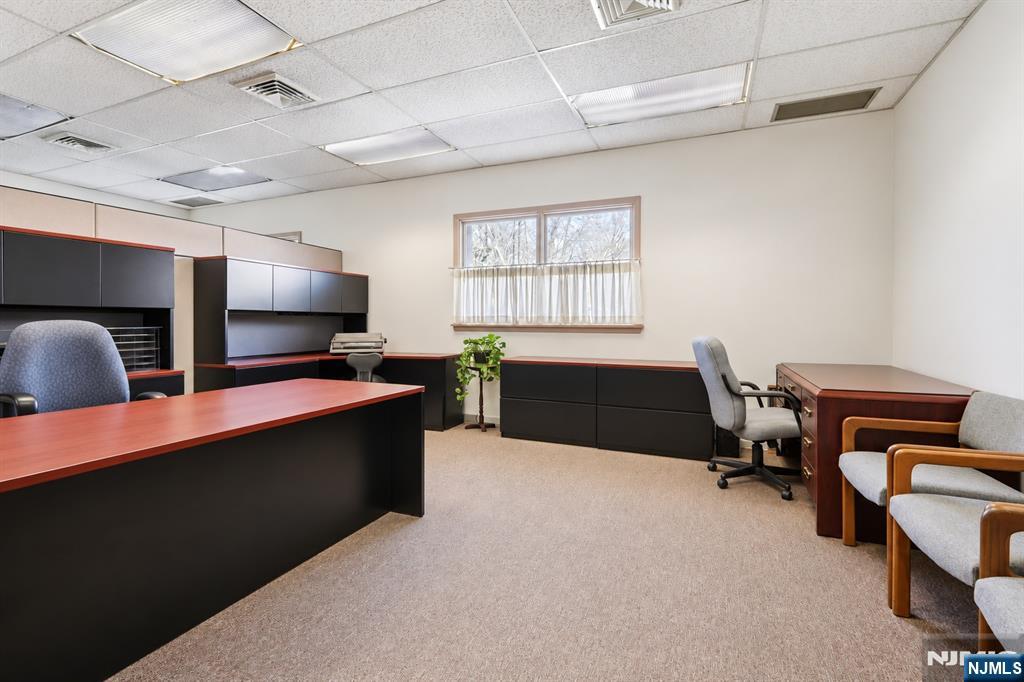Office interior with multiple desks, built-in cabinetry, and guest chairs.