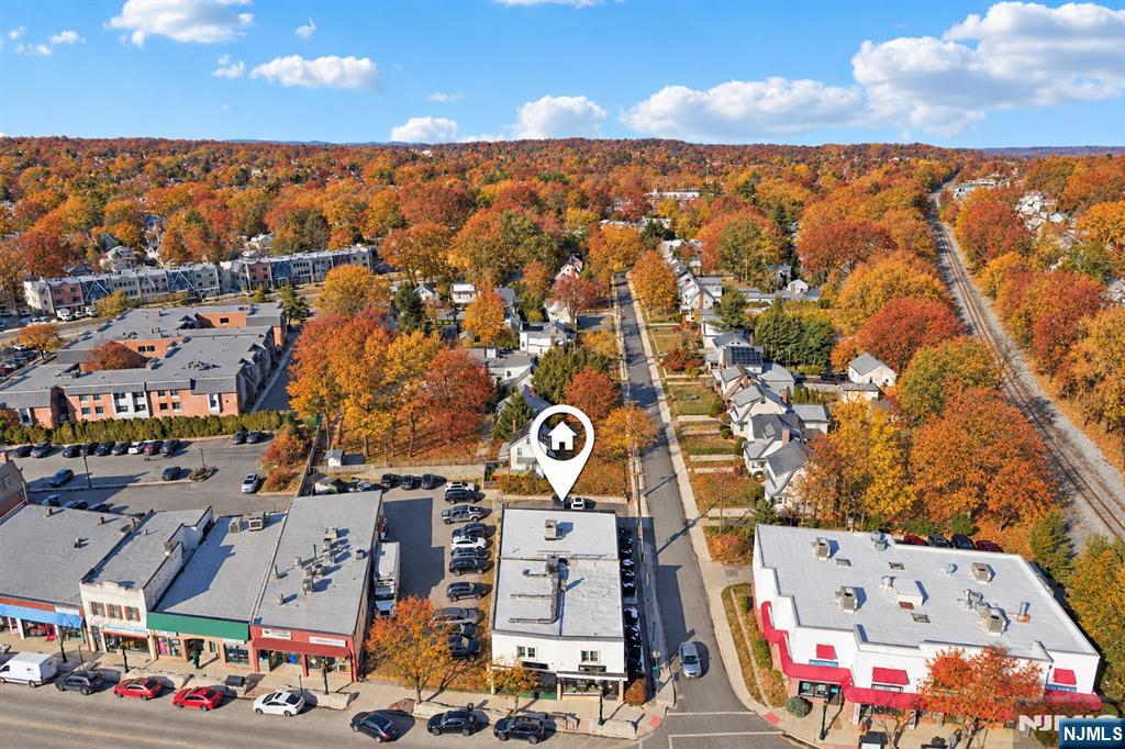 Aerial view of a suburban street and nearby homes amid autumn foliage, with the property marked by a map pin.