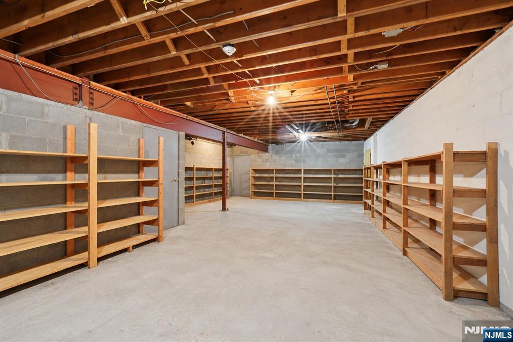 Unfinished basement storage room with exposed joists and empty wooden shelves along the walls.