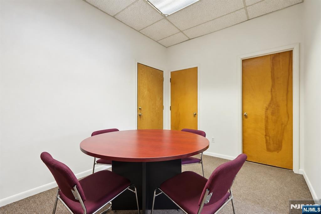 Conference room with a round wood table, burgundy chairs, and three wooden doors.