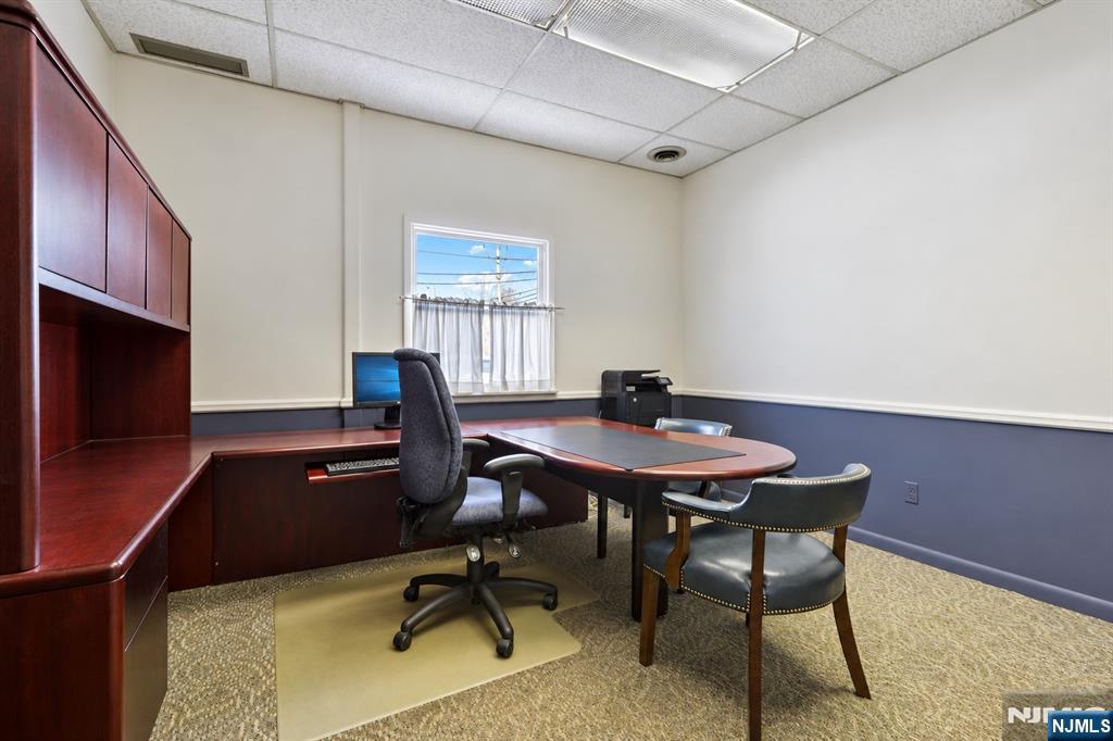Office with built-in wood desk, computer, and a small meeting table.