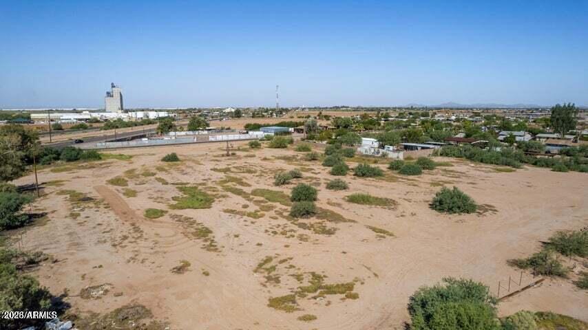Aerial view of a vacant sandy parcel with desert shrubs and nearby development.