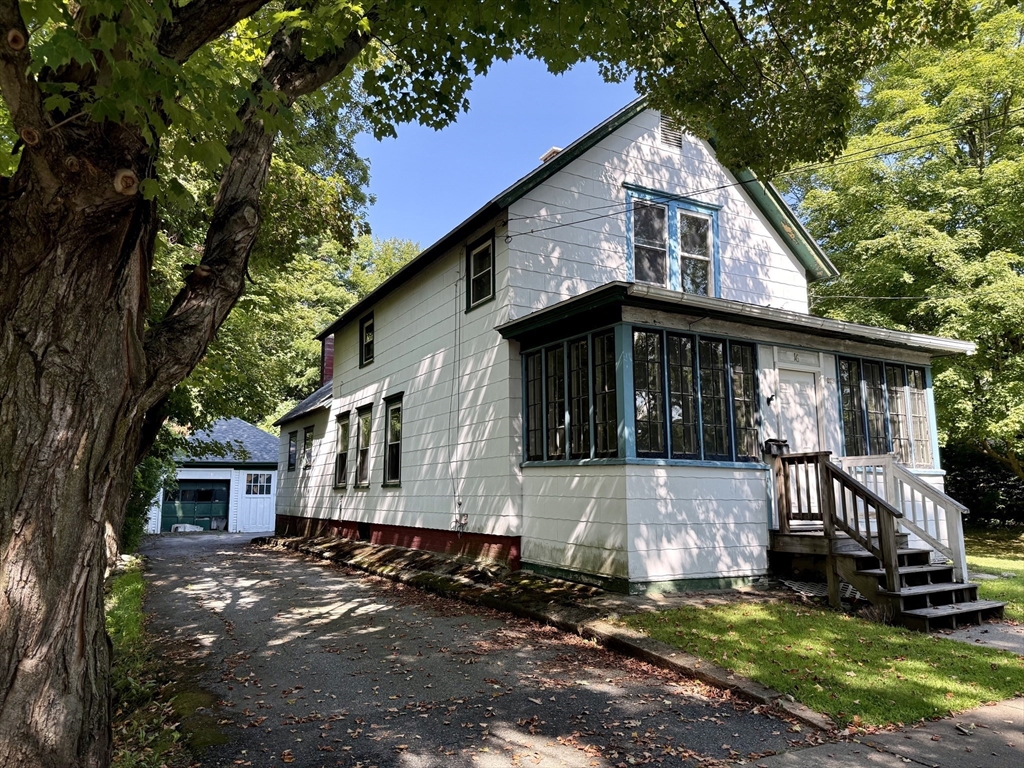 White two-story house with an enclosed sunroom, front porch, and detached garage.