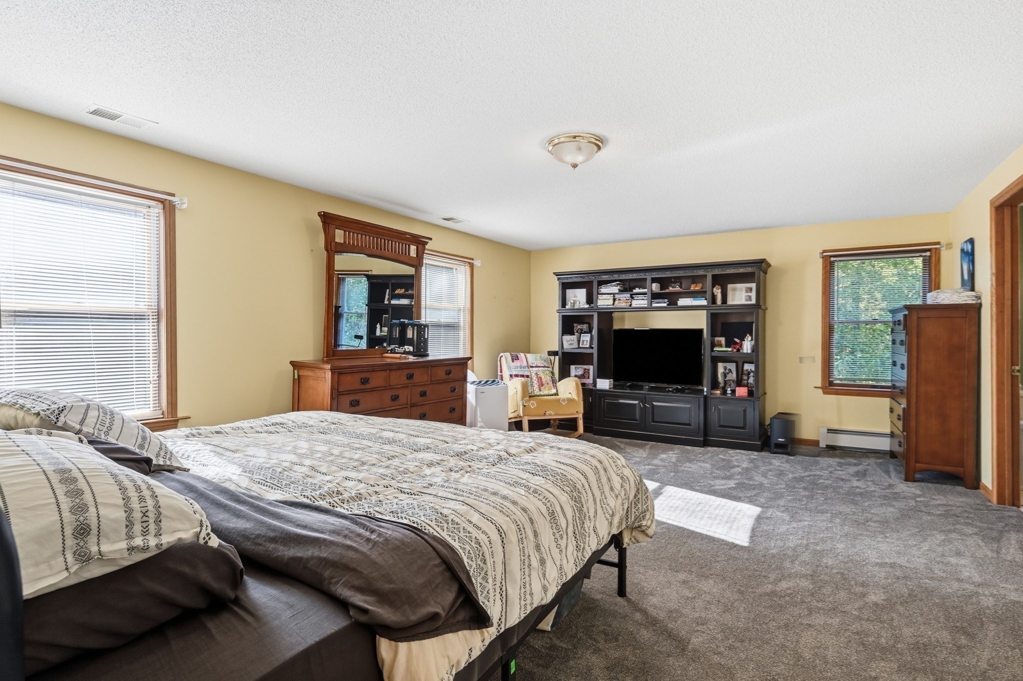 Furnished bedroom with a large patterned bed and dark entertainment center.