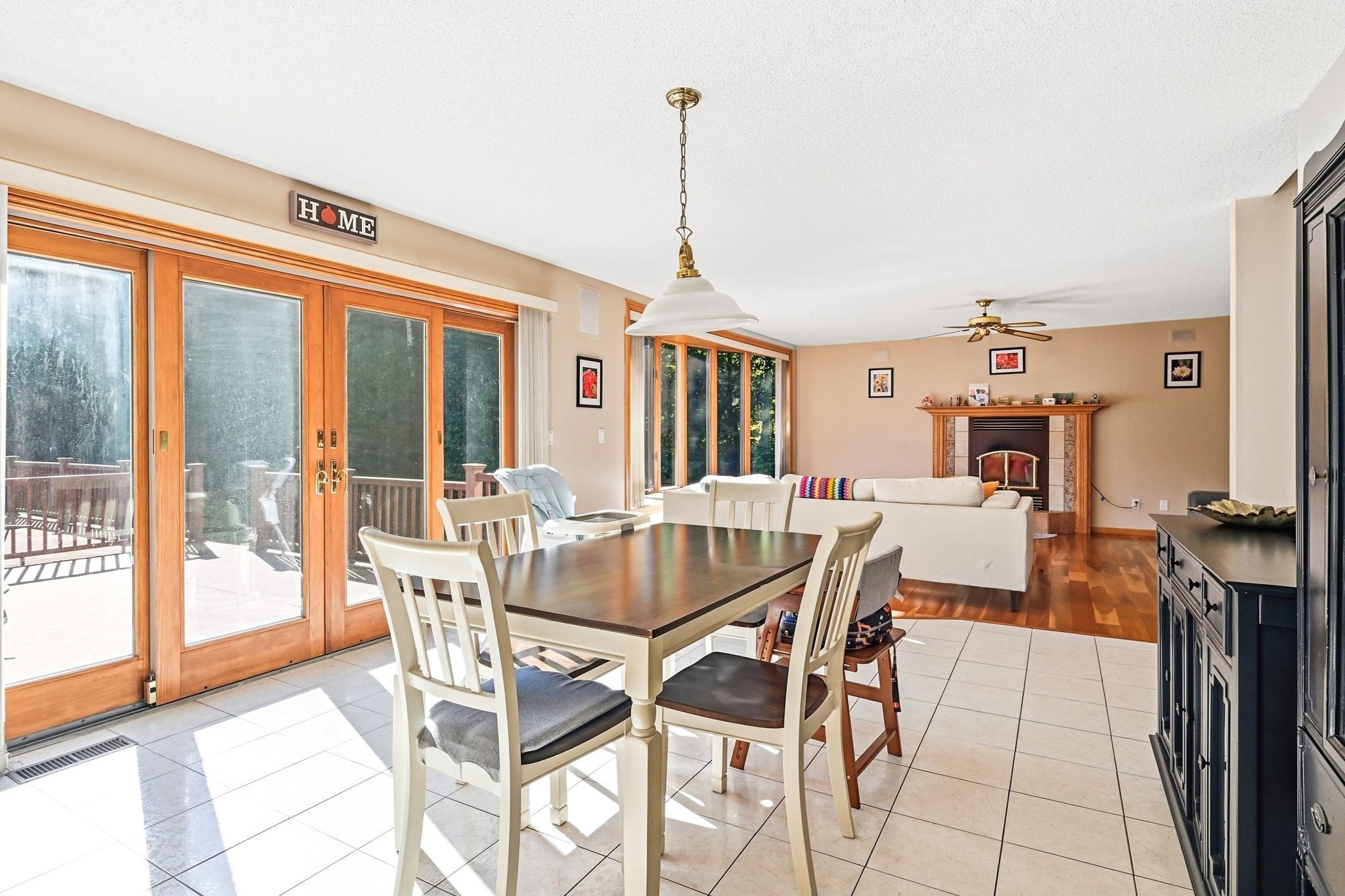 Dining area with wood-trimmed glass doors, a dark table, and a living room fireplace beyond.