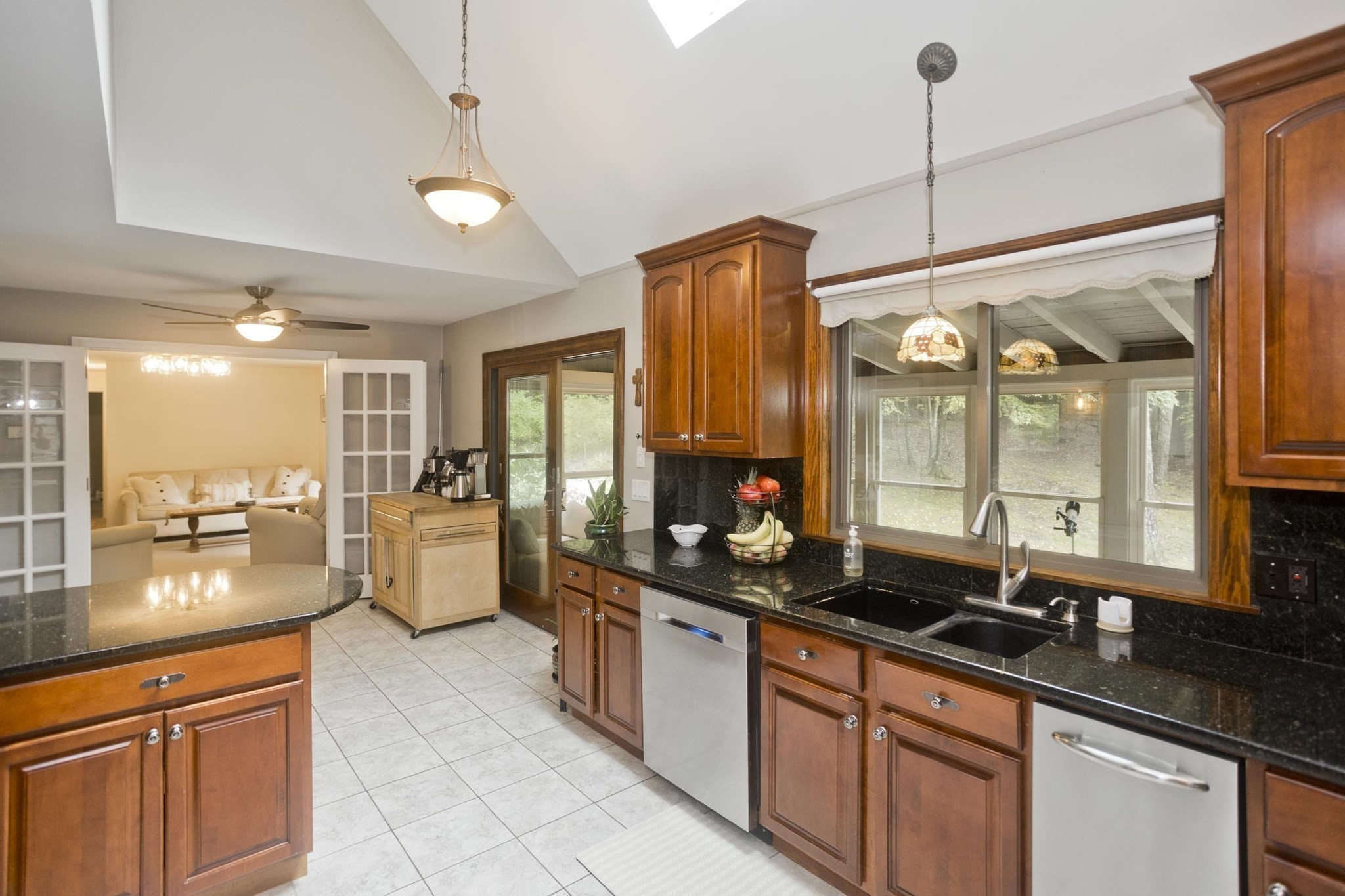 Kitchen with cherry cabinets, black countertops, a double sink, and French doors to the living room.