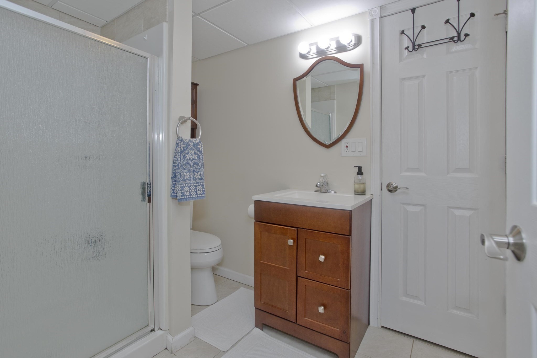 Bathroom with a wood vanity, framed mirror, and frosted-glass shower enclosure.